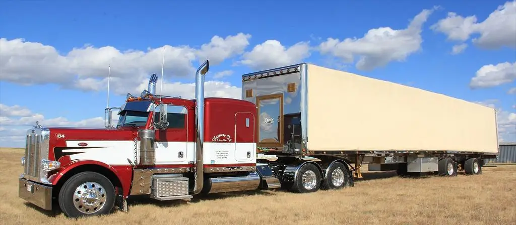 Red and white Farmers Oil Peterbilt pulling a Conestoga curtain-side trailer