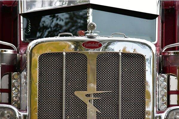 Close-up of a polished Peterbilt grille wearing the Farmers Oil Flying F emblem