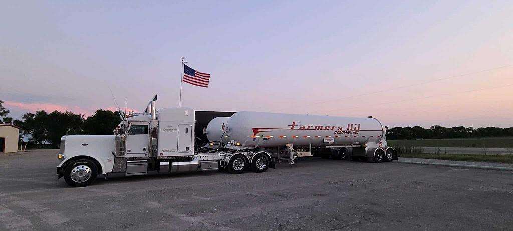 White Farmers Oil Peterbilt and propane transport parked at sunset beneath an American flag