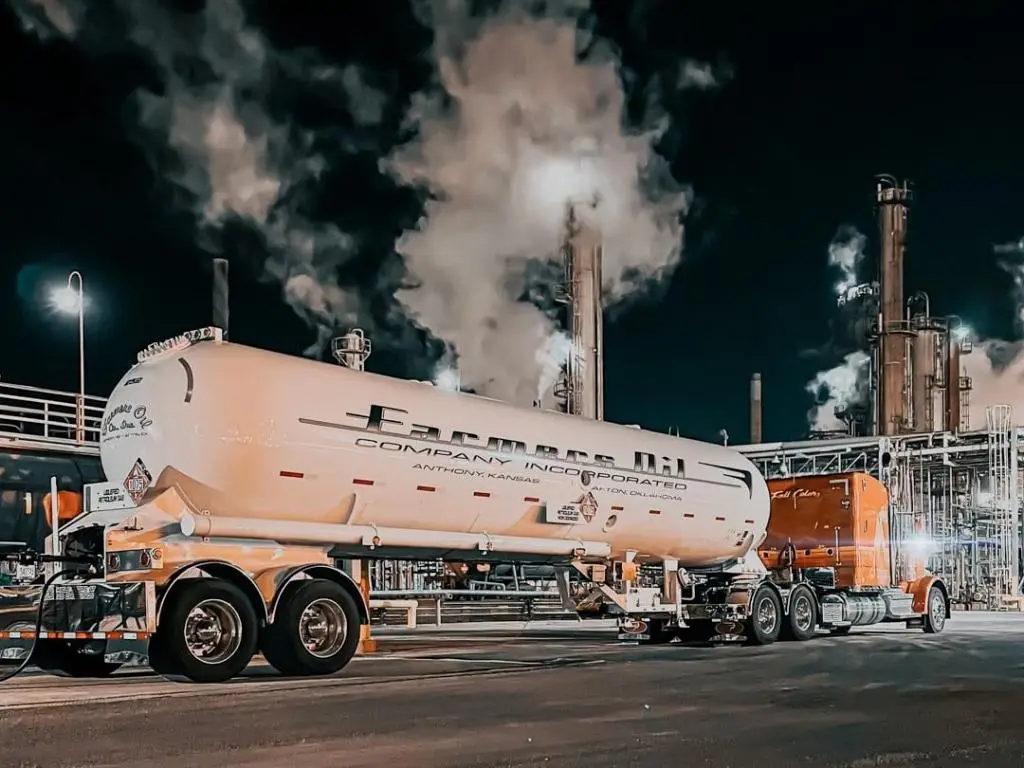 Farmers Oil tank trailer at night with refinery steam rising behind it