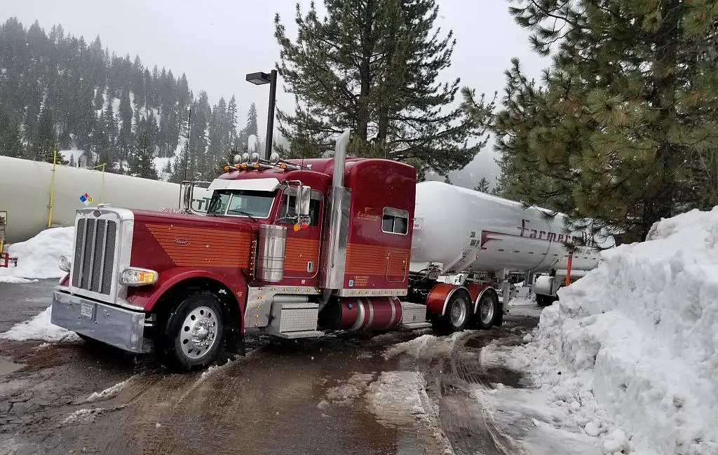 Red Farmers Oil Peterbilt and tank trailer on a snowy lot