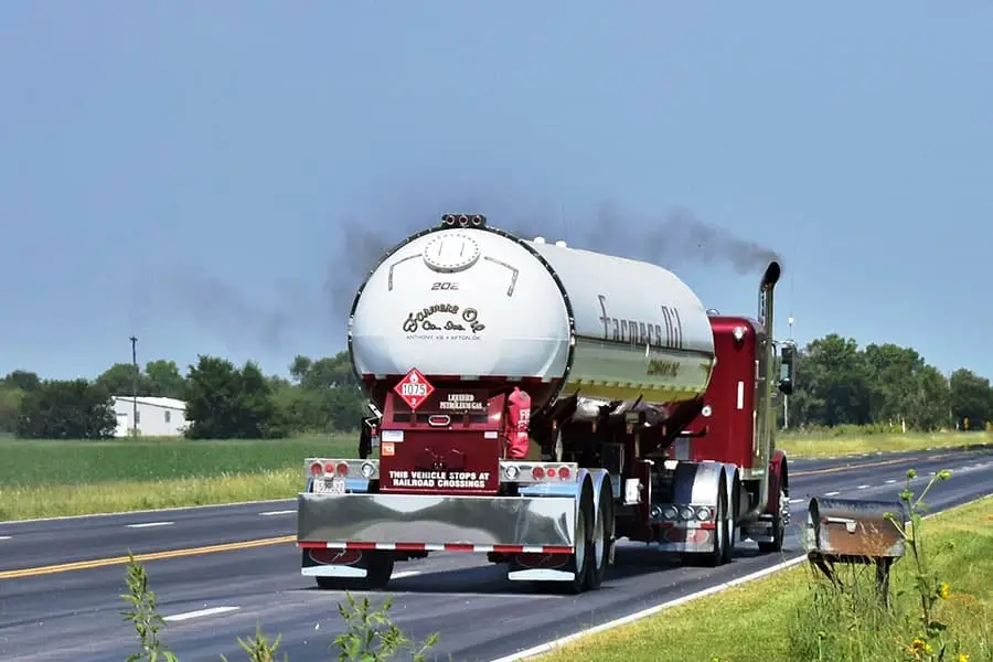 Farmers Oil tanker on a two-lane highway with stacks smoking