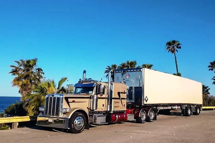 Farmers Oil truck and van trailer among palm trees on the coast